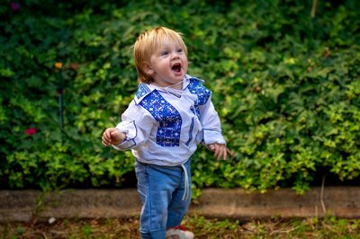 Cibi son in Ukrainian vyshyvanka shirt in the garden — Novaparent surrogacy family from Australia